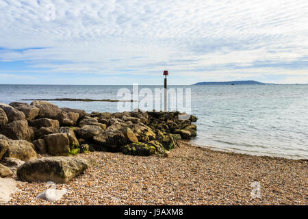 Warning post on a rocky promontory at Ringstead Bay, Dorset, England, UK, Portland Bill in the distance Stock Photo