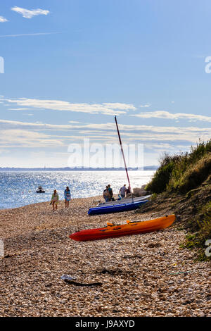 Three sailing boats and holidaymakers on the shingle beach at Ringstead Bay, Dorset, England, UK Stock Photo