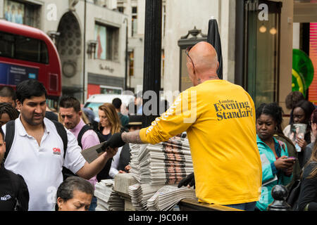 An Evening Standard newspaper vendor at Oxford Circus tube station, London, UK Stock Photo