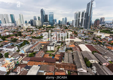 Low residential buildings contrats with the tall and modern office buildings of the Kuningan business district in Jakarta, Indonesia capital city. Stock Photo