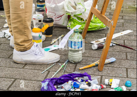 Paint, brushes and artist's paraphernalia on pavement as an artist paints a street scene on Grand Parade, Cork, Ireland. Stock Photo