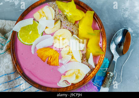 Pink tropical smoothie bowl (carambola, pineapple, coconut). Love for a healthy vegan food concept
