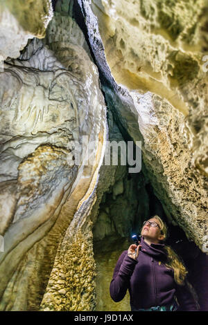 Woman lighting a cave with flashlight, limestone cave, Luxmore Cave, Kepler Track, Fiordland National Park, South Island Stock Photo