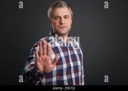 Just stop. Confident charismatic handsome guy warning you about something while holding his hand in front of him and asking you to stop Stock Photo