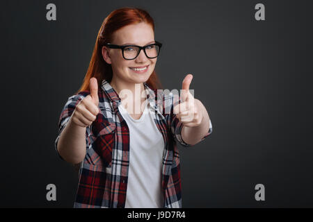 Great decision. Nice radiant sweet woman supporting the idea while expressing her attitude by using commonly known gesture Stock Photo