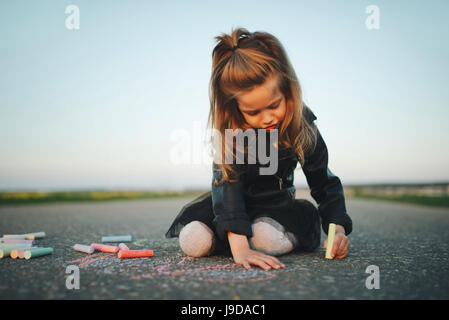 little girl draws pictures on asphalt Stock Photo