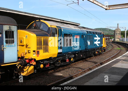 Class 37 diesel electric  locomotive, 37 403 Isle of Mull, with a loco hauled passenger train at Carnforth railway station, Lancashire. Stock Photo