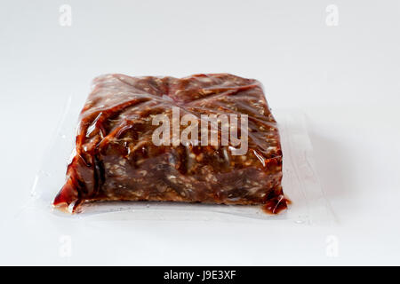 Ground frozen venison meat wrapped in plastic against white background Stock Photo
