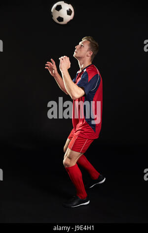 Professional Soccer Player Heading Ball In Studio Stock Photo