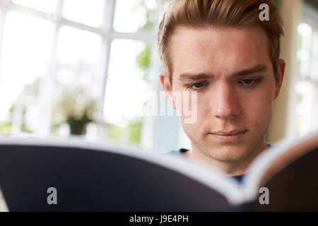 Close Up Of Young Man Reading Book At Home Stock Photo