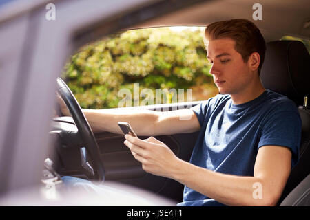 Young Man Sending Text Message Whilst Driving Stock Photo