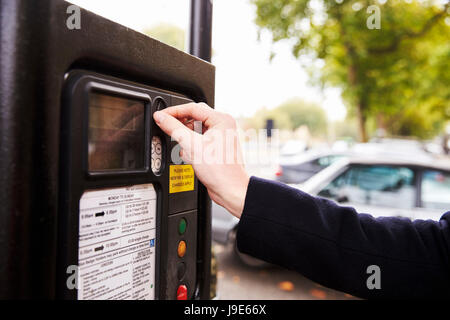 Close Up Of Man Putting Money In Parking Meter For Ticket Stock Photo