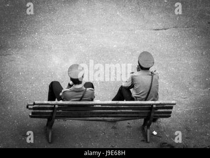 Two police officers maybe thinking, mayby just resting on the bench. Perhaps philosophers? Comunism times in Poland - 1988. Black and white photo. Stock Photo