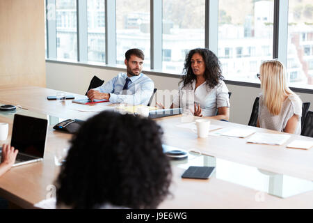 Businesswoman Leads Meeting Around Board Table Stock Photo