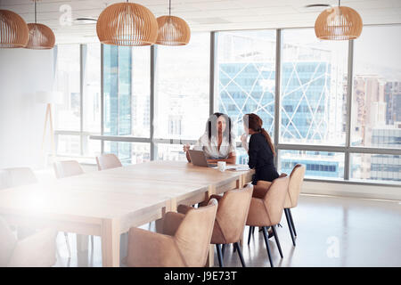 Two Businesswomen Using Laptop In Boardroom Meeting Stock Photo