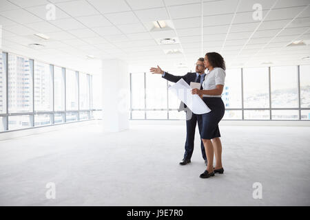 Businesspeople Meeting To Look At Plans In Empty Office Stock Photo