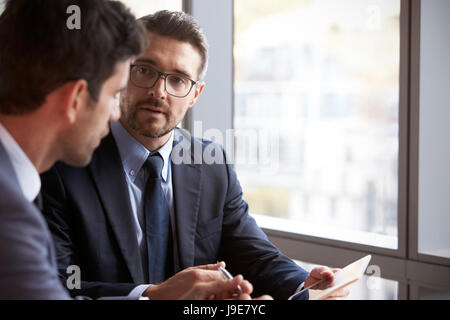 Two Businessmen Using Digital Tablet In Office Meeting Stock Photo