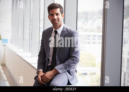 Portrait Of Young Businessman Sitting By Window In Office Stock Photo