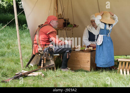 Roundhead Soldier with his family in an encampment at a Sealed Knot English Civil war reenactment event.  Charlton Park, Malmesbury, Wiltshire, UK Stock Photo