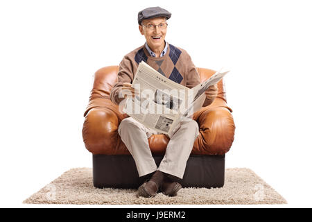 Joyful mature man with a newspaper sitting in a leather armchair and looking at the camera isolated on white background Stock Photo