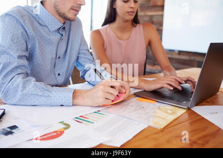 Young man and woman working together at an office desk, crop Stock Photo