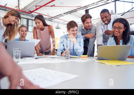 Young business team gathered around two laptops in an office Stock Photo