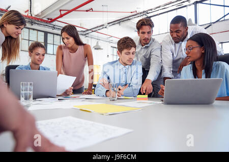 Young business team gathered around two laptops in an office Stock Photo