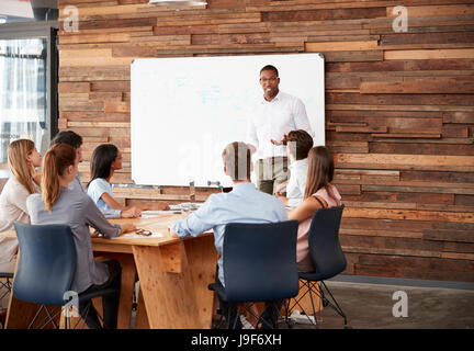 Young black man at whiteboard giving a business presentation Stock Photo