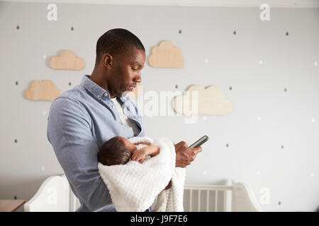 Father Holding Newborn Baby Son Using Mobile Phone Stock Photo