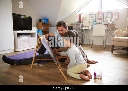 Father And Children Drawing On Chalkboard In Playroom Stock Photo