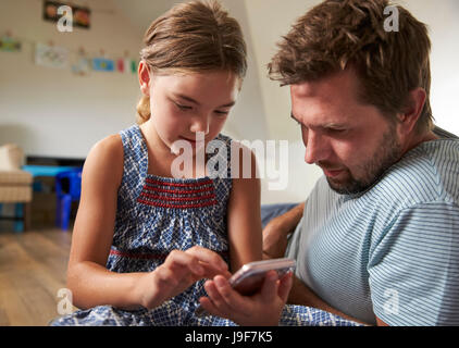 Father And Daughter Using Mobile Phone In Playroom Together Stock Photo