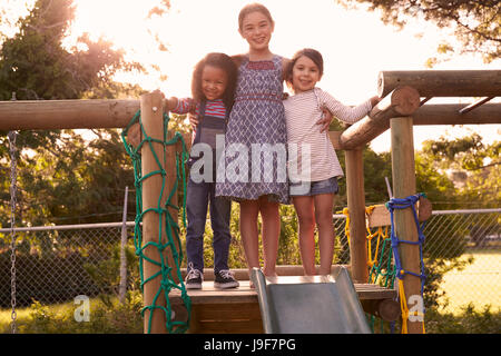 Three Girls Playing Outdoors At Home On Garden Slide Stock Photo
