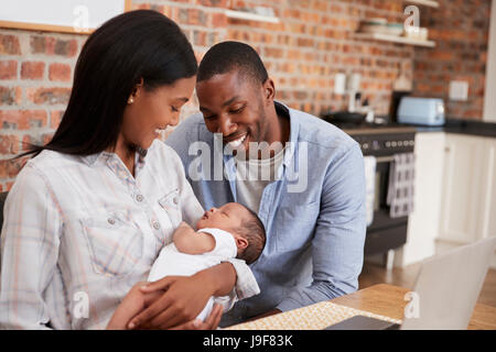 Mother Working On Laptop Holds Newborn Son With Father Stock Photo