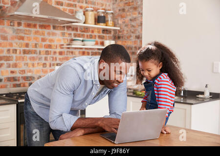 Father And Daughter Using Laptop In Kitchen At Home Stock Photo