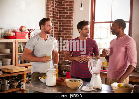Three male friends drinking homemade smoothies in kitchen Stock Photo