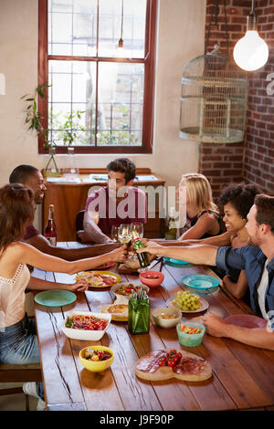 Six friends making a toast at a dinner party, vertical Stock Photo