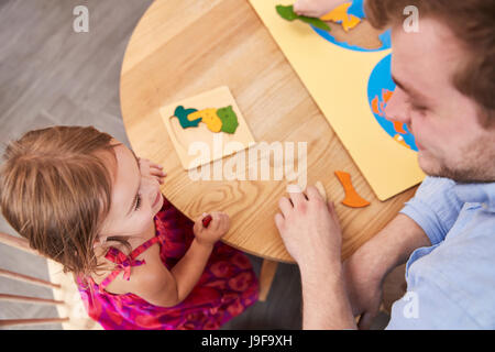 Teacher And Pupil Using Wooden Shapes In Montessori School Stock Photo