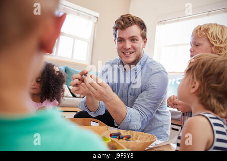 Teacher And Pupils Working At Tables In Montessori School Stock Photo