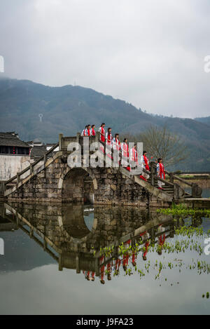 Women dressed in traditional clothes on a bridge, Ancient Chengkan Village, founded during the Three Kingdoms period and arranged on fengshui principl Stock Photo