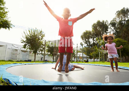 Children At Montessori School Having Fun On Outdoor Trampoline Stock Photo