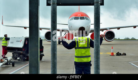 Rear view of airport ground crew directing plane into apron parking space Stock Photo