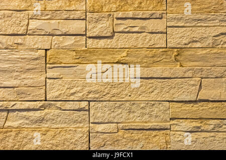 The wall is lined with beige rectangular tiles with a voluminous, rough surface. Stock Photo