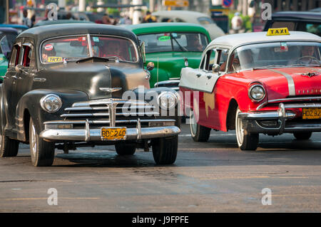 HAVANA, CUBA - CIRCA JUNE, 2011: Vintage American taxi cars share the road on a street in Centro. Stock Photo