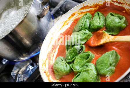 Green Tortelloni. Typical Bolognese homemade fresh stuffed pasta at the end of cooking just a moment before serving. Green pasta is kneaded with flour Stock Photo