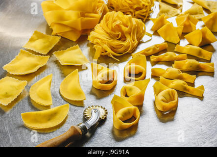 Various kinds of traditional italian really homemade pasta, some stuffed. Tagliatelle, fettuccine, tortelloni, tortellini, ravioli, pappardelle. Stock Photo
