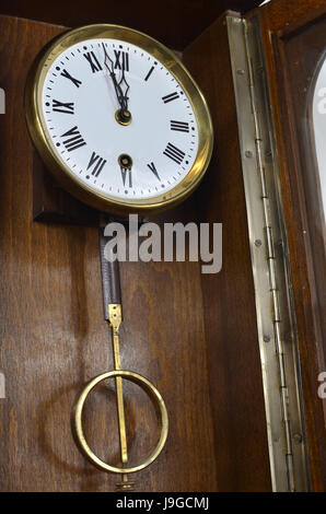 Wall wooden clock with pendulum in vintage style Stock Photo
