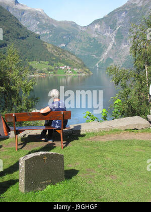 A old woman sits alone on a bench. Looks into the distance Stock Photo
