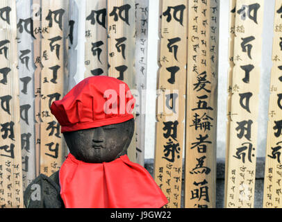 A long row of Buddha statues wearing red knitted hats in the entrance to  a small Buddhist temple in Yanaka, Tokyo. Stock Photo