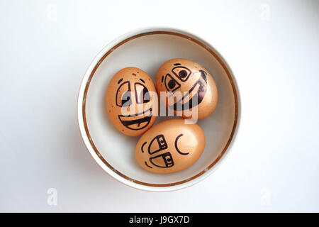 Egg with a cheerful painted face. Photo for your design. To swim in a plate three eggs. Boiled eggs are swarfed in a steep. Stock Photo