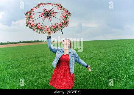 A happy woman with umbrella in green field Stock Photo